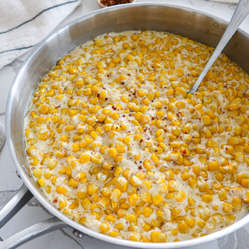 Creamed corn in a large, stainless steel skillet.