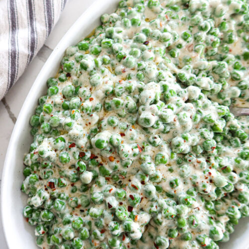Creamed peas in an oval white serving dish.