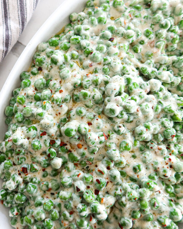 Creamed peas in an oval white serving dish.