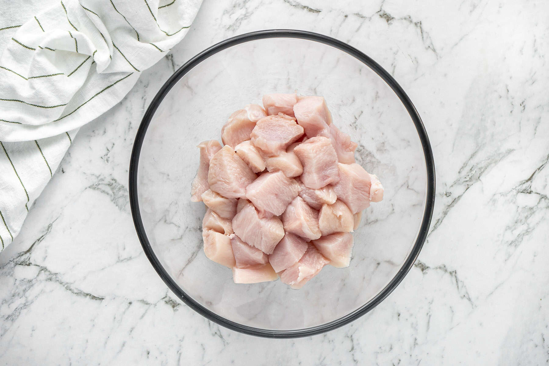 Cubed chicken in a glass mixing bowl.