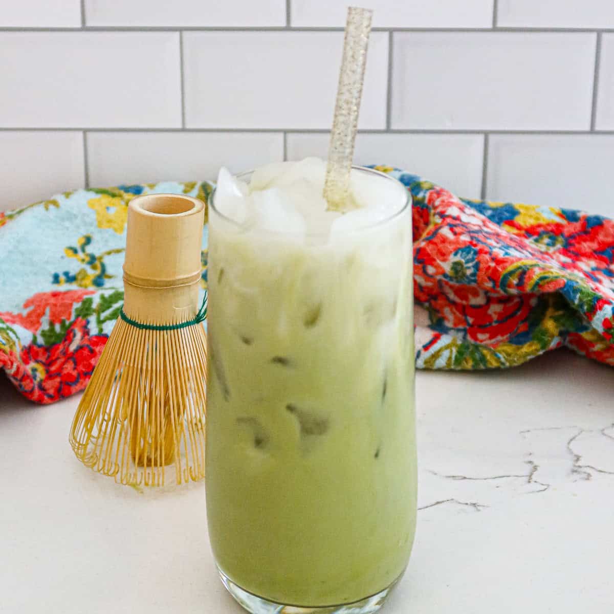 Iced matcha latte in a clear drinking glass with straw.