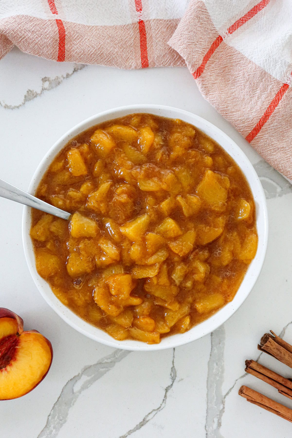 Peach compote in a white bowl with spoon.