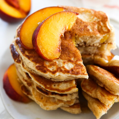 Peach pancakes on a white serving plate.