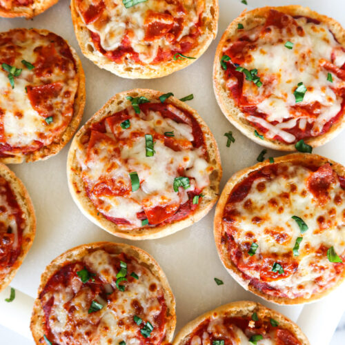 Mini pizzas on a white cutting board.