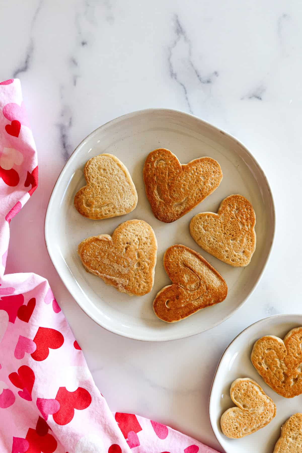 Heart shaped pancakes on white plates.