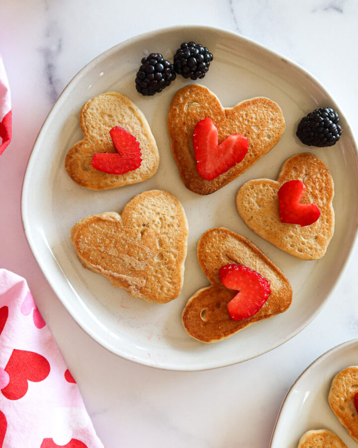 Heart shaped pancakes with berries on top.