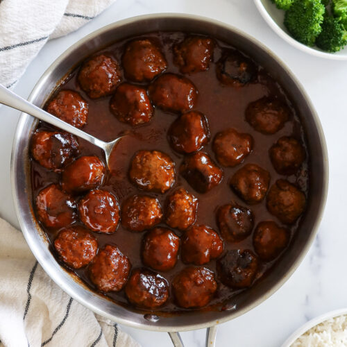 Sweet and sour meatballs in a stainless skillet.