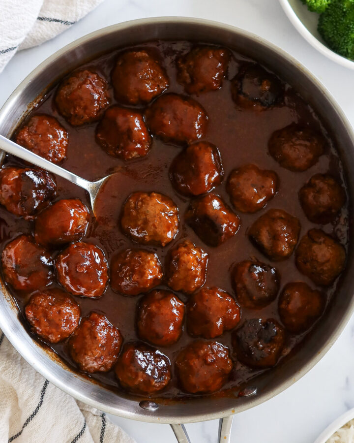Sweet and sour meatballs in a stainless skillet.