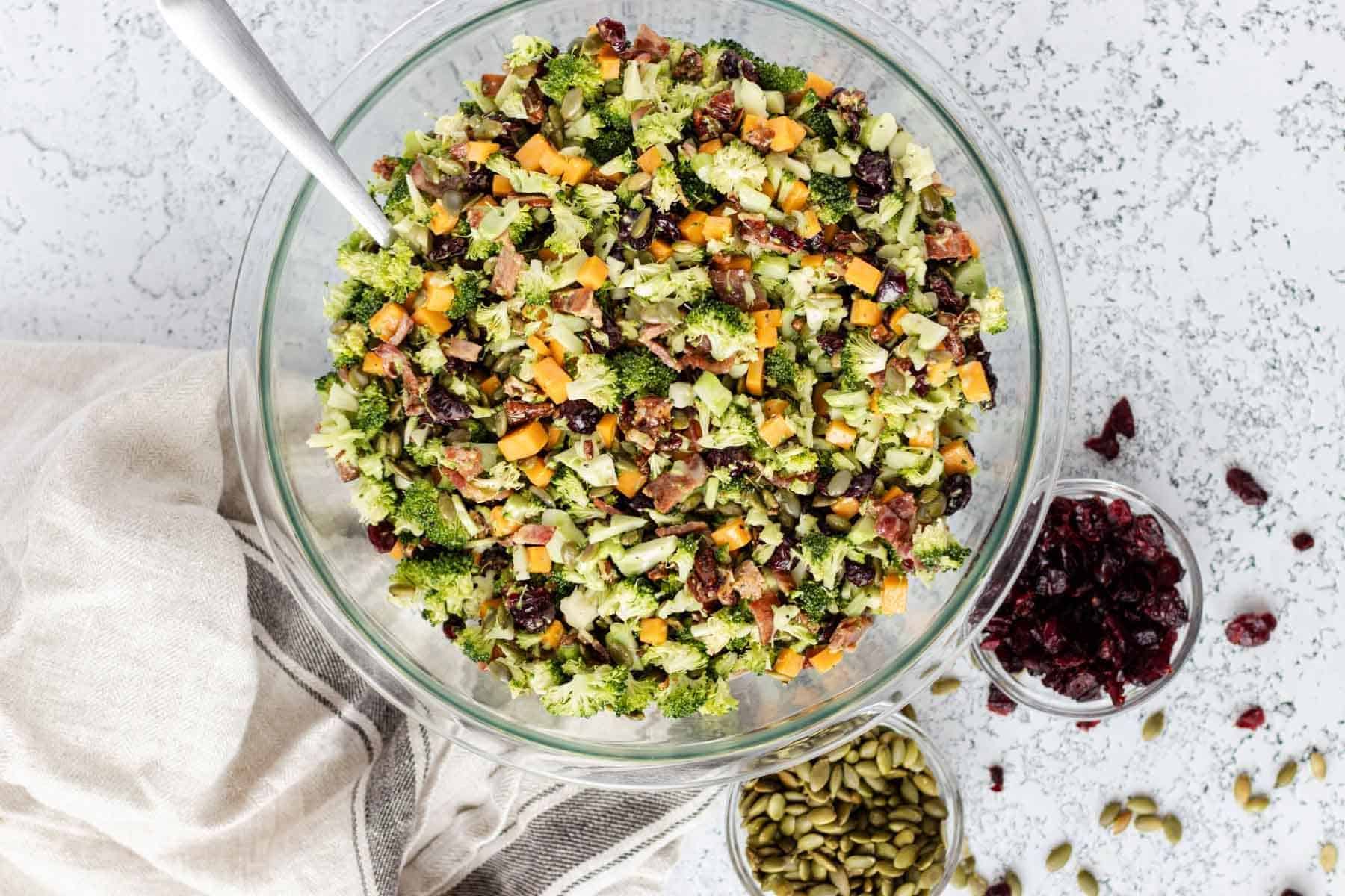 Broccoli crunch salad in a large glass bowl with serving spoon.