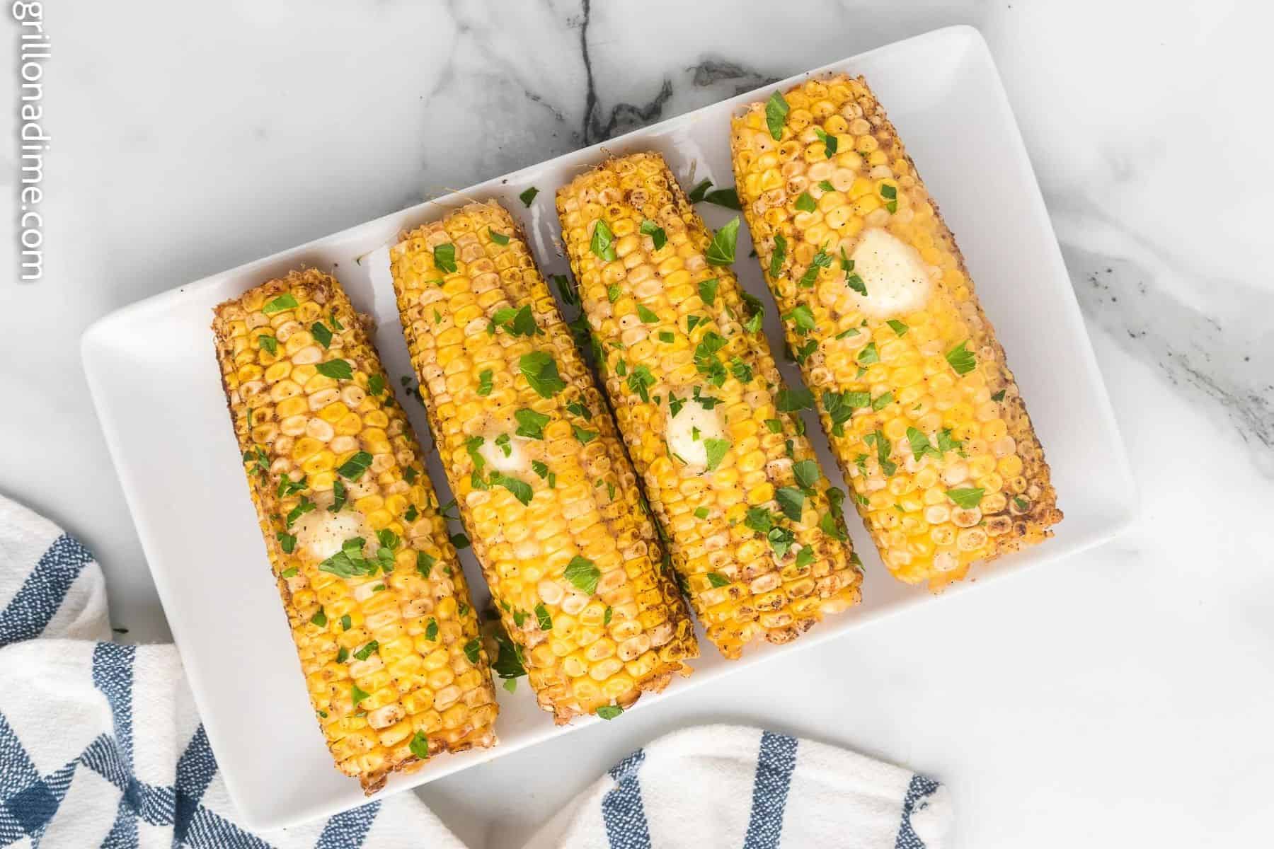 Corn on the cob on a white serving plate.