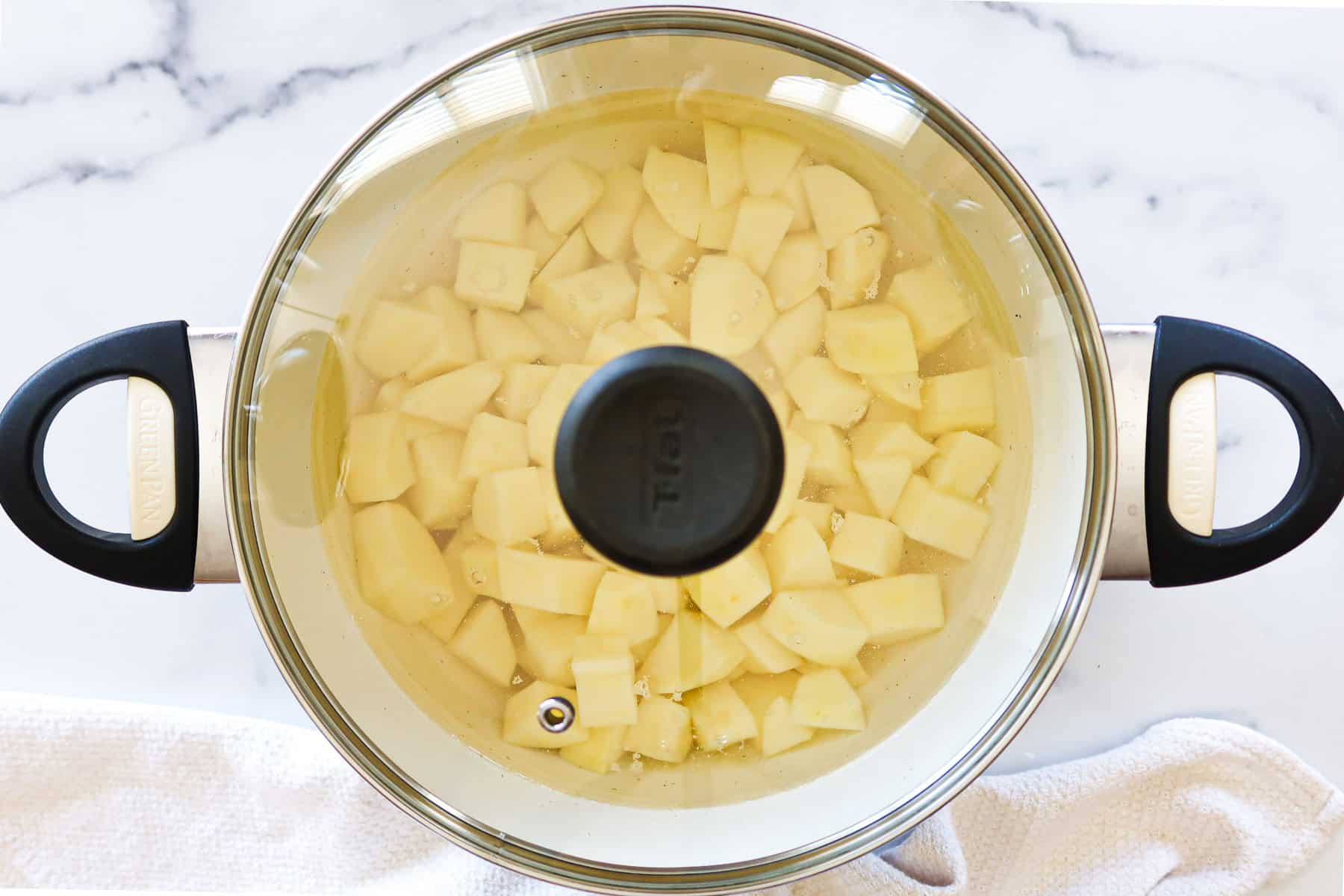 Peeled and cubed potatoes and water in a lidded pot.