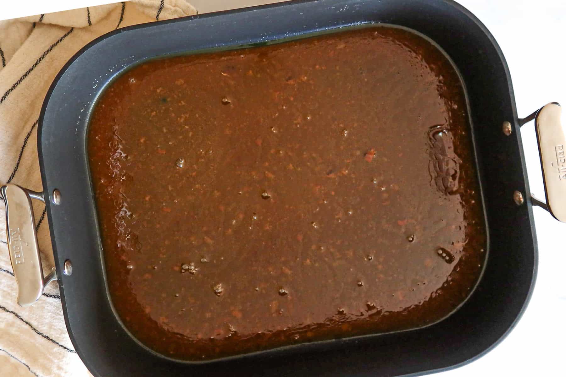 Ham drippings in black roasting pan.