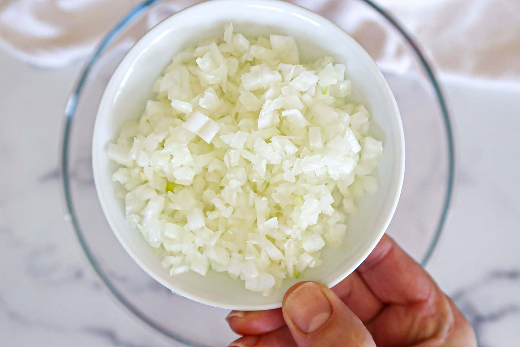Finely minced onion in a small, white bowl.