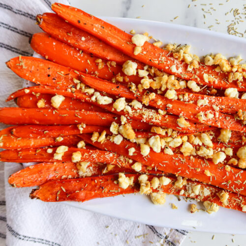 Roasted honey feta carrots on a white serving plate.