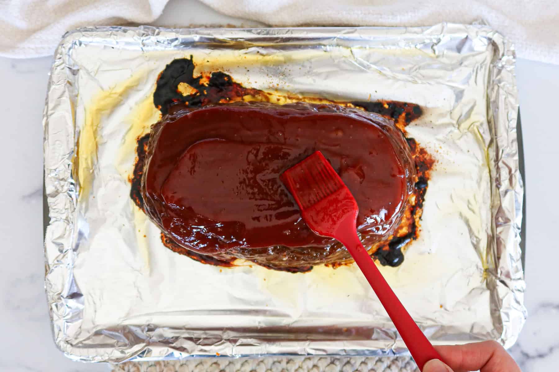 Brushing glaze onto meatloaf.