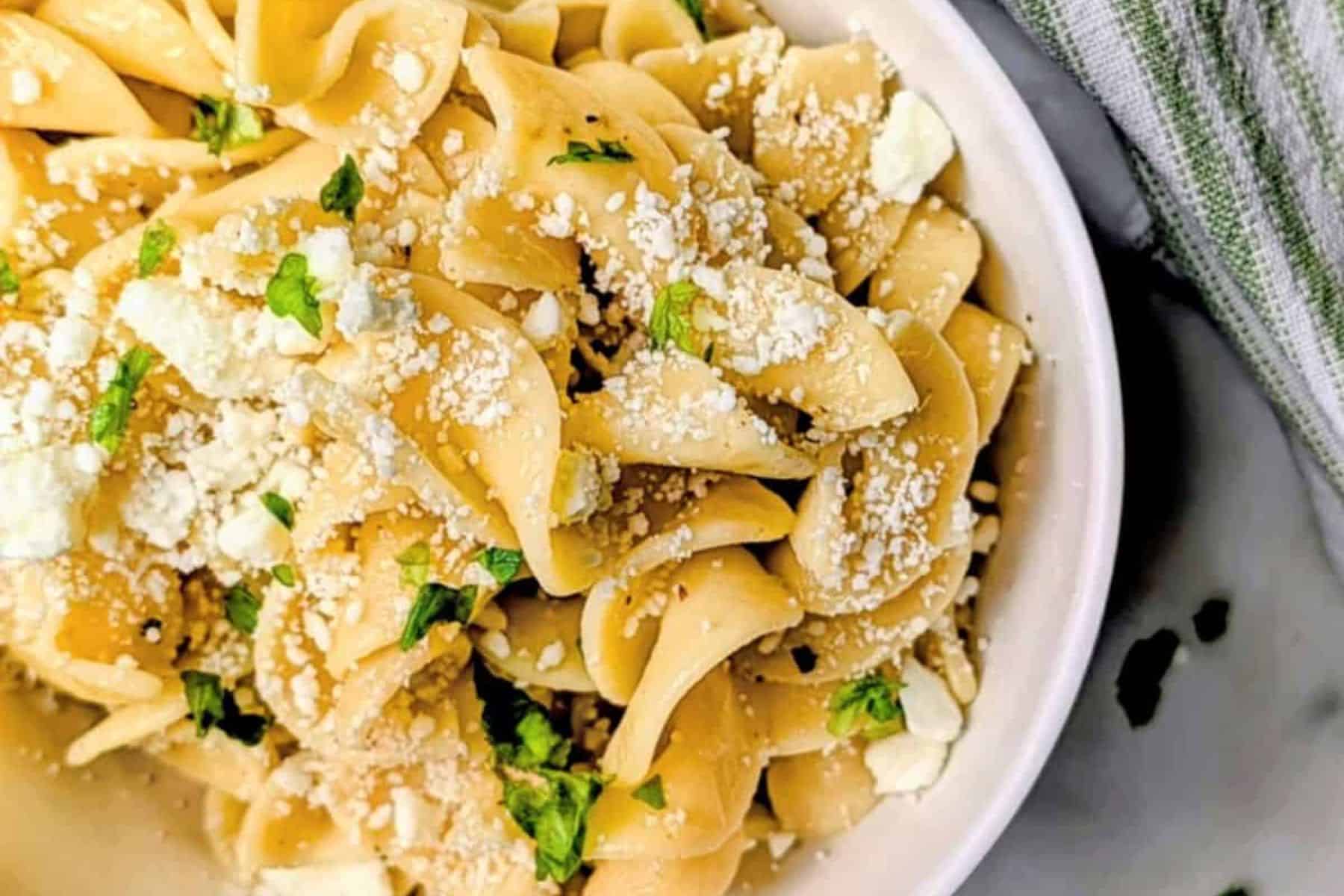 Buttered noodles in a white serving dish.