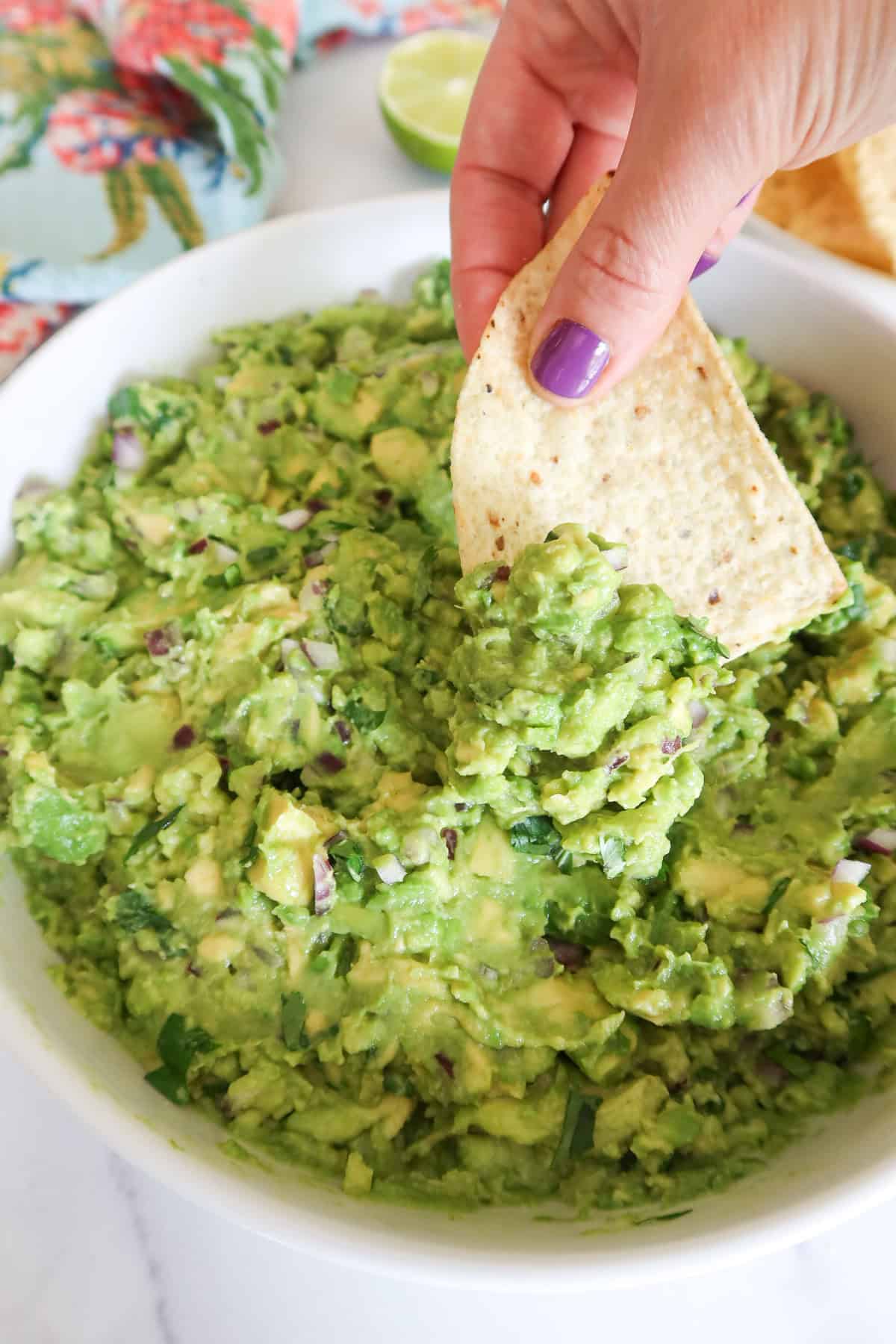 Scooping guacamole with a tortilla chip.