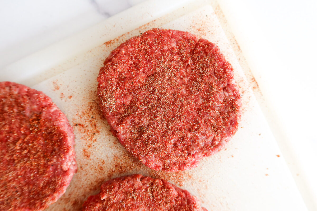 Burgers sprinkled with seasonings.