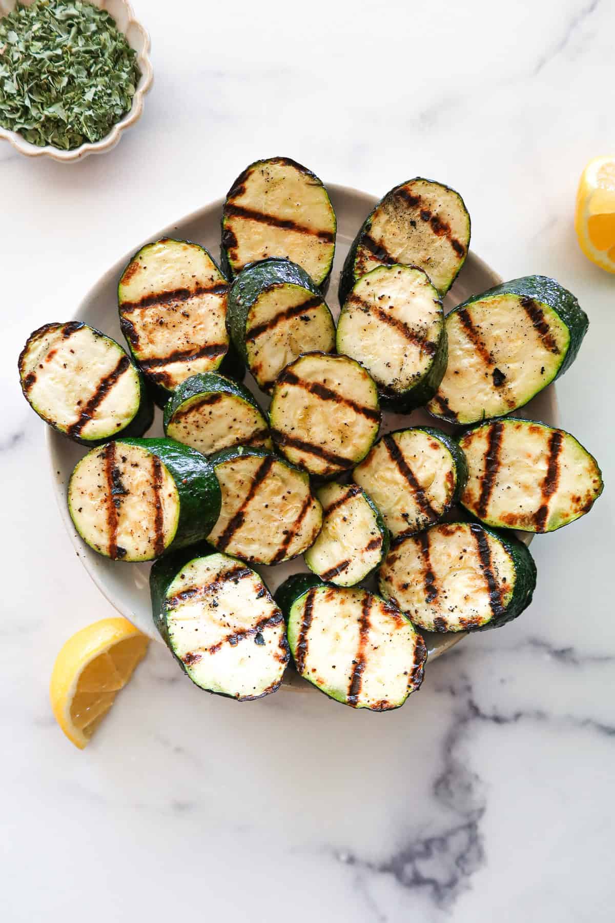 Grilled zucchini on a white serving plate.