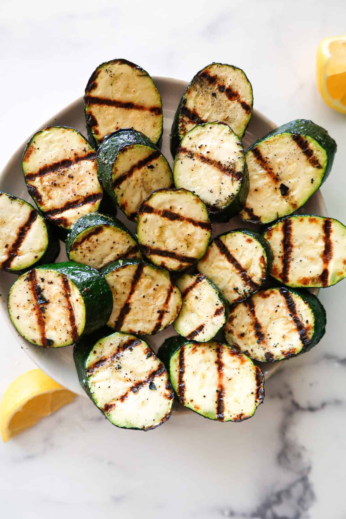 Grilled zucchini on a white serving plate.