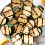 Grilled zucchini on a white serving plate.