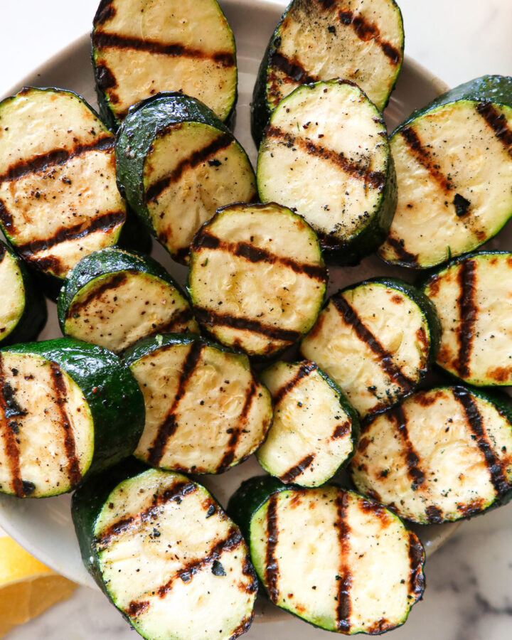 Grilled zucchini on a white serving plate.