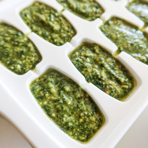 Pesto portioned into an ice cube tray for freezing.