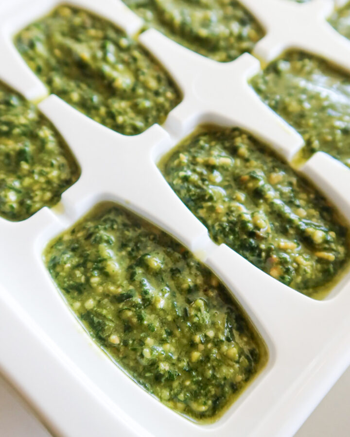 Pesto portioned into an ice cube tray for freezing.