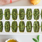 Pesto portioned into an ice cube tray for freezing.