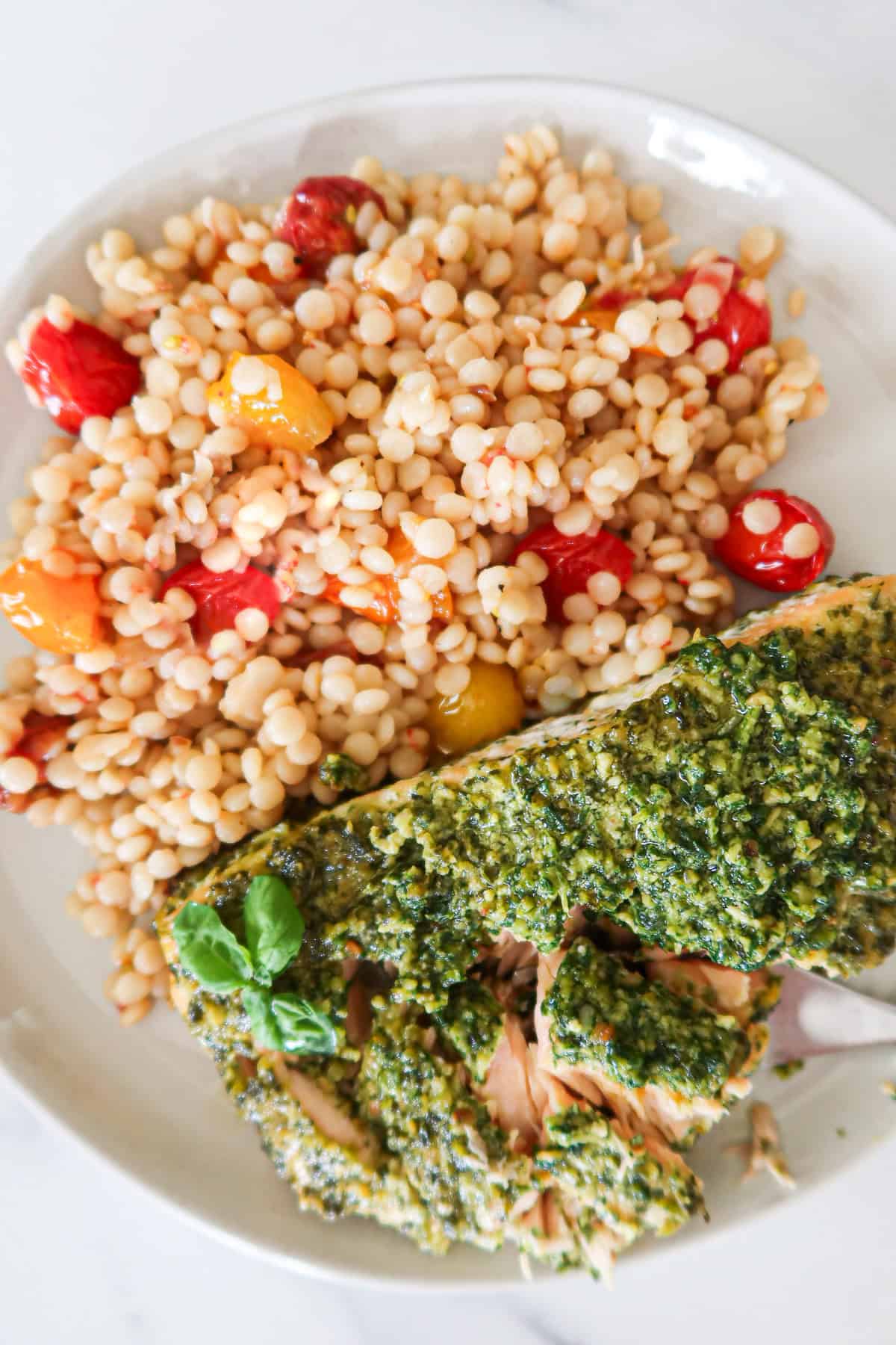 Pesto salmon on a plate with a side of couscous.