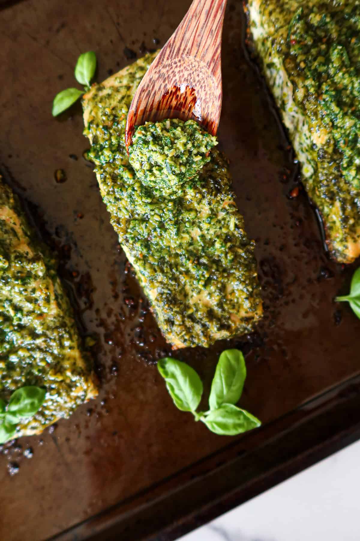 Spooning more pesto onto salmon.