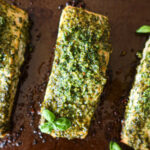 Closeup of roasted pesto salmon on a baking sheet.