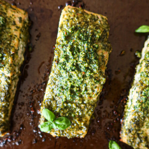 Closeup of roasted pesto salmon on a baking sheet.