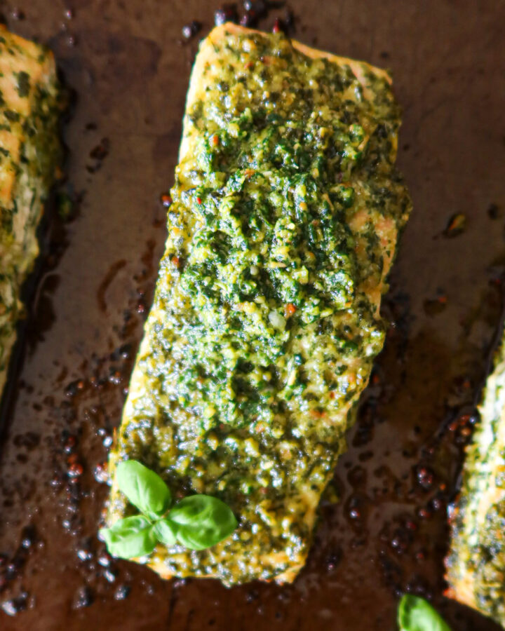 Closeup of roasted pesto salmon on a baking sheet.
